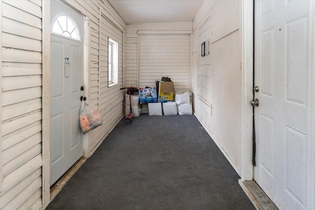 interior space with dark colored carpet and wood walls