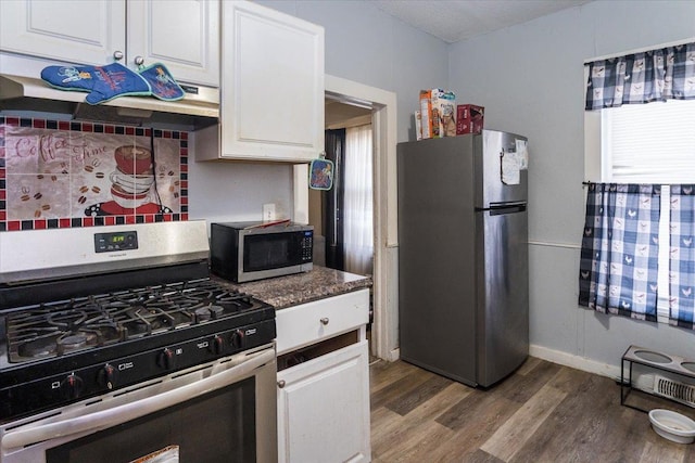 kitchen featuring dark stone countertops, white cabinets, stainless steel appliances, and wood-type flooring