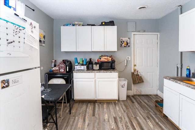 kitchen featuring white cabinets, white fridge, dark hardwood / wood-style floors, and sink