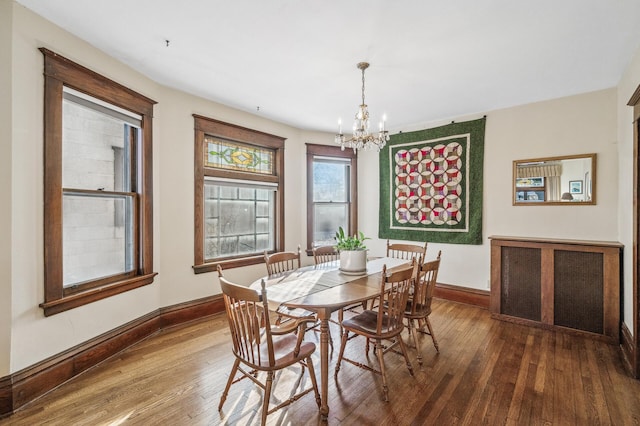 dining space with dark hardwood / wood-style flooring and an inviting chandelier