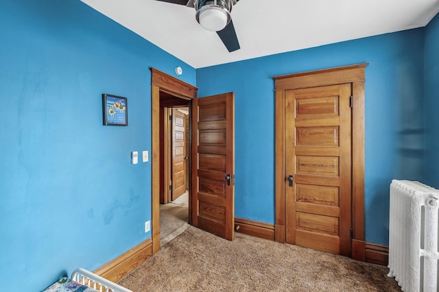 carpeted bedroom with ceiling fan and radiator heating unit