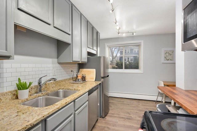 kitchen featuring light wood-type flooring, light stone counters, gray cabinetry, sink, and dishwasher