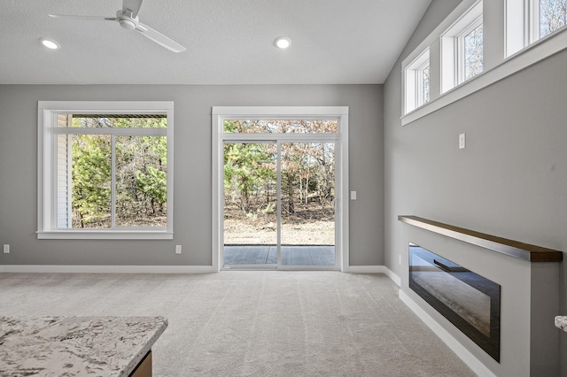 unfurnished living room featuring ceiling fan, light colored carpet, and a textured ceiling