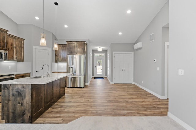 kitchen featuring sink, stainless steel appliances, an island with sink, decorative light fixtures, and dark brown cabinets