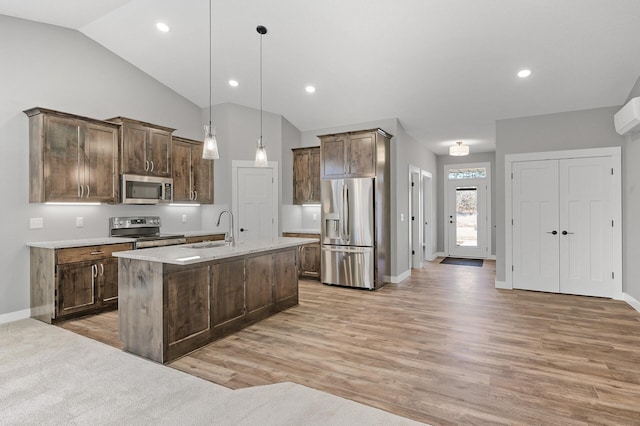 kitchen featuring appliances with stainless steel finishes, sink, a center island with sink, hardwood / wood-style floors, and hanging light fixtures