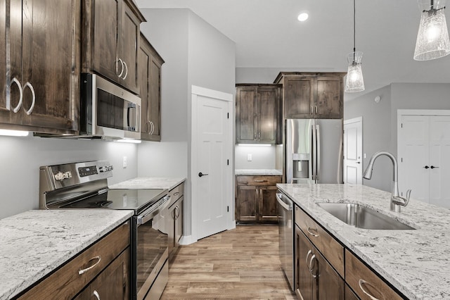 kitchen featuring hanging light fixtures, sink, light stone countertops, appliances with stainless steel finishes, and dark brown cabinets