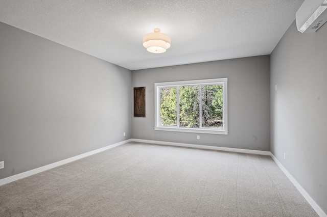 unfurnished room with a wall unit AC, carpet floors, and a textured ceiling