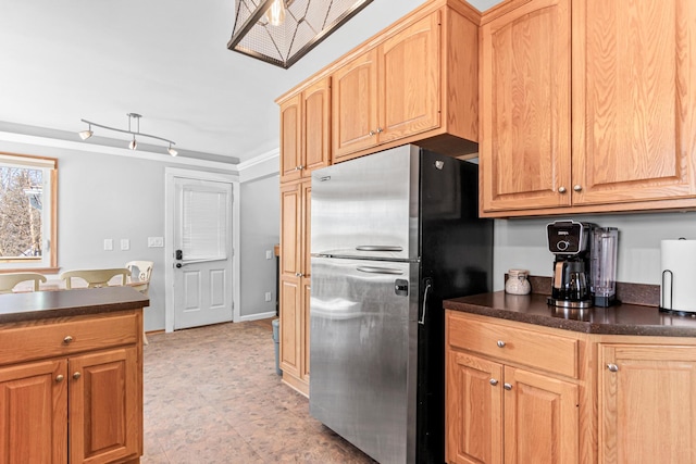 kitchen with dark countertops, light brown cabinets, and freestanding refrigerator