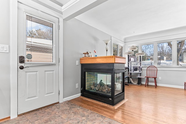 living area with a multi sided fireplace, plenty of natural light, baseboards, and wood finished floors