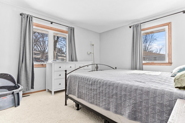 bedroom featuring multiple windows, light colored carpet, and baseboards