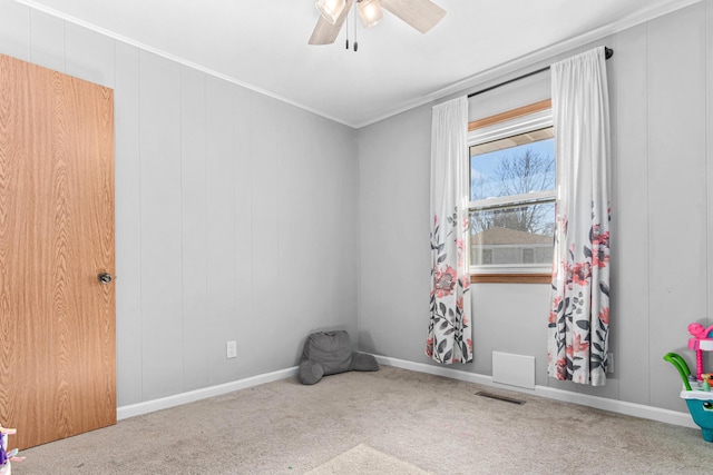 carpeted empty room with visible vents, baseboards, ceiling fan, and ornamental molding