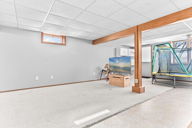 basement with a drop ceiling, baseboards, and carpet flooring