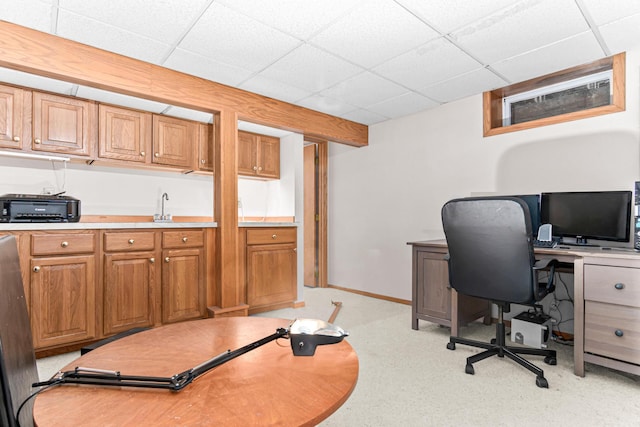 office featuring light carpet, a toaster, a paneled ceiling, and baseboards