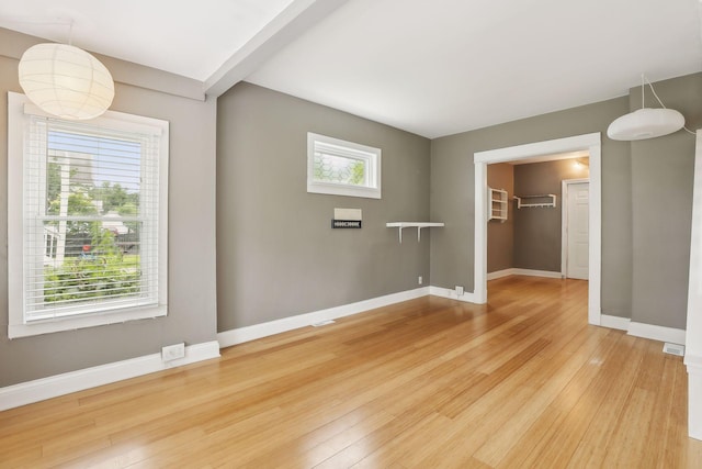 unfurnished bedroom featuring multiple windows, a spacious closet, a closet, and hardwood / wood-style flooring