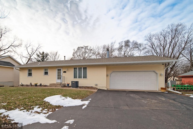 single story home with cooling unit, a garage, and a lawn