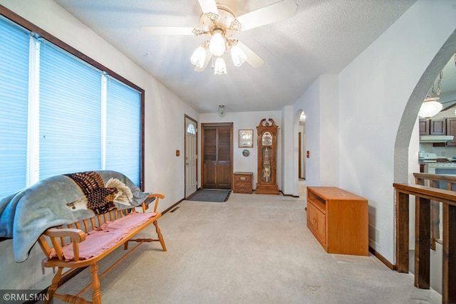 living area with light carpet, ceiling fan, and plenty of natural light