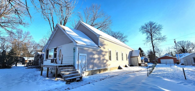 snow covered property featuring a garage and an outdoor structure