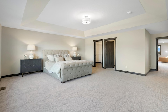 bedroom with light carpet and a tray ceiling