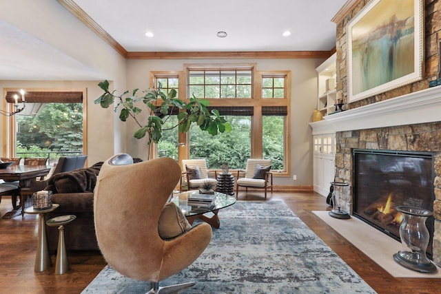 living area featuring ornamental molding, dark hardwood / wood-style flooring, a stone fireplace, and a notable chandelier