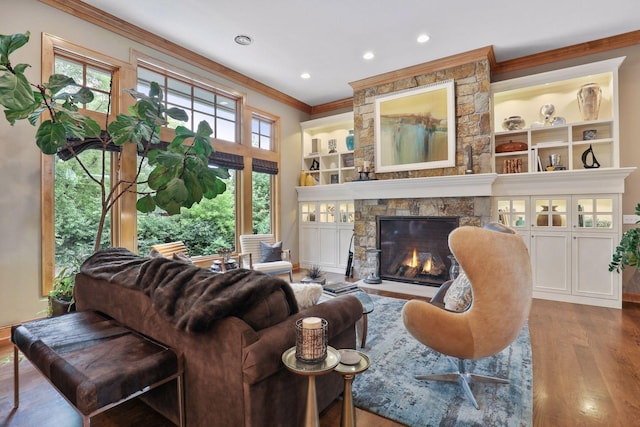 living room featuring hardwood / wood-style flooring, ornamental molding, a fireplace, and built in shelves