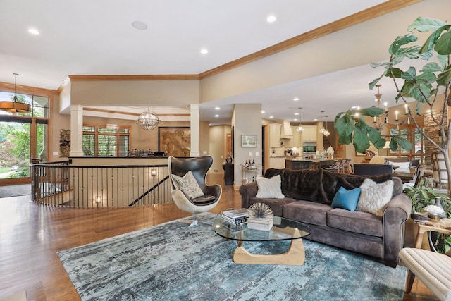 living room with ornate columns, crown molding, hardwood / wood-style flooring, and a chandelier