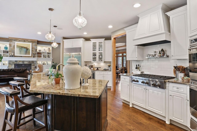 kitchen with white cabinetry, appliances with stainless steel finishes, decorative light fixtures, and an island with sink