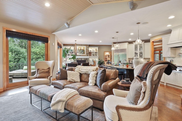 living room with a large fireplace, lofted ceiling, and light hardwood / wood-style flooring