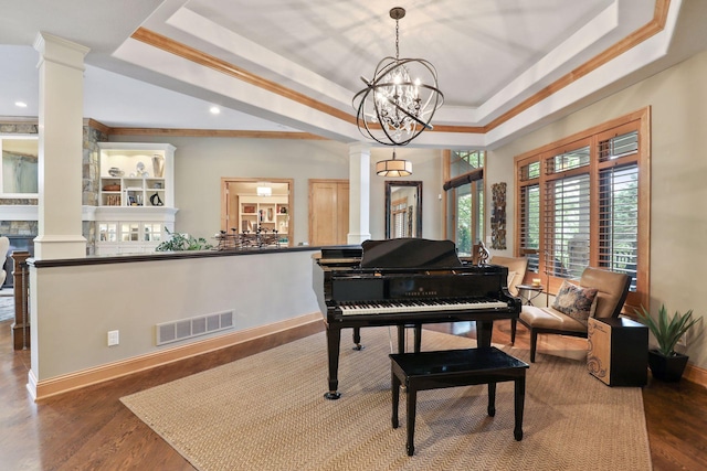 miscellaneous room with crown molding, wood-type flooring, a raised ceiling, and decorative columns