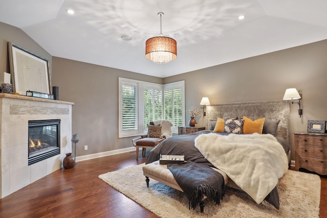 bedroom featuring lofted ceiling, dark hardwood / wood-style floors, and a tiled fireplace