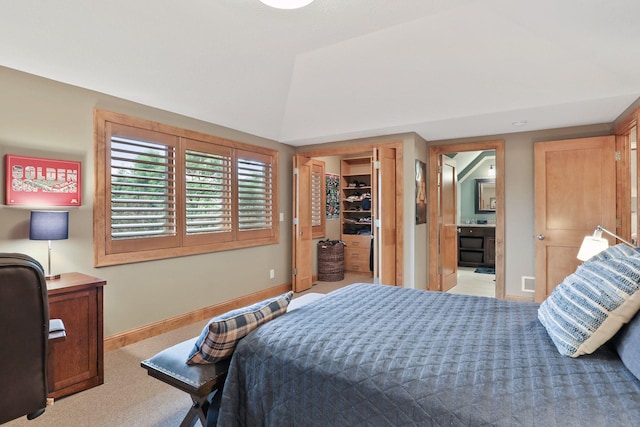 carpeted bedroom featuring vaulted ceiling, a spacious closet, ensuite bath, and a closet