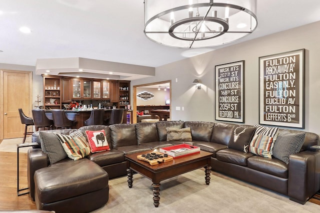 living room with light wood-type flooring, a chandelier, and indoor bar