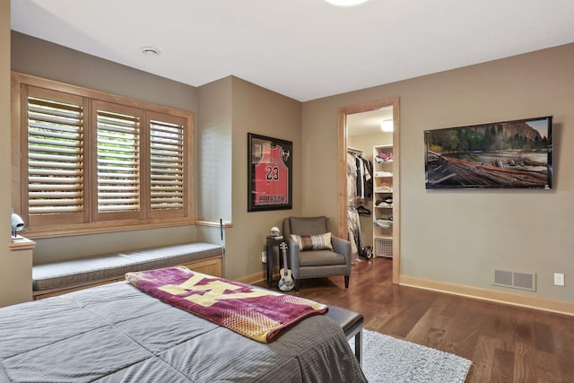 bedroom featuring dark wood-type flooring, a spacious closet, and a closet