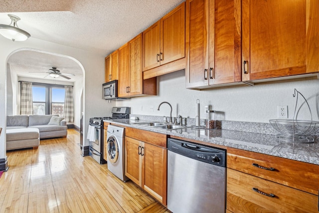 kitchen with sink, a textured ceiling, light stone counters, stainless steel appliances, and washer / clothes dryer