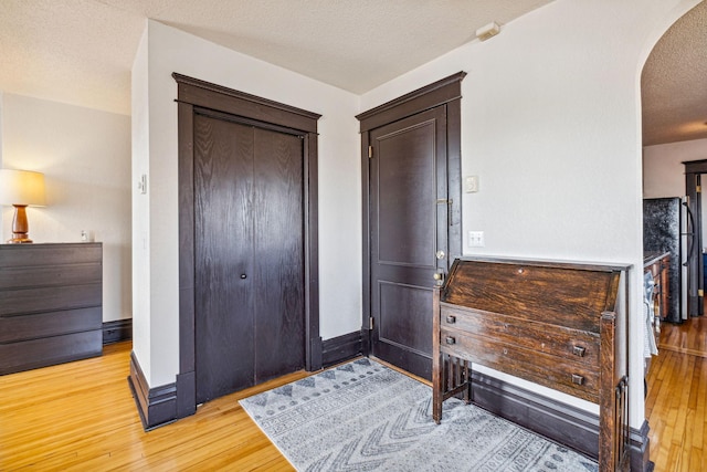 interior space featuring black refrigerator, a closet, light hardwood / wood-style floors, and a textured ceiling