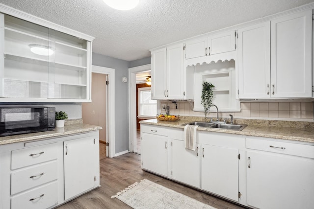 kitchen featuring black microwave, white cabinetry, and light countertops