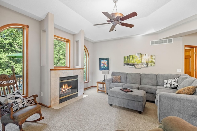 carpeted living room with ceiling fan and a tile fireplace