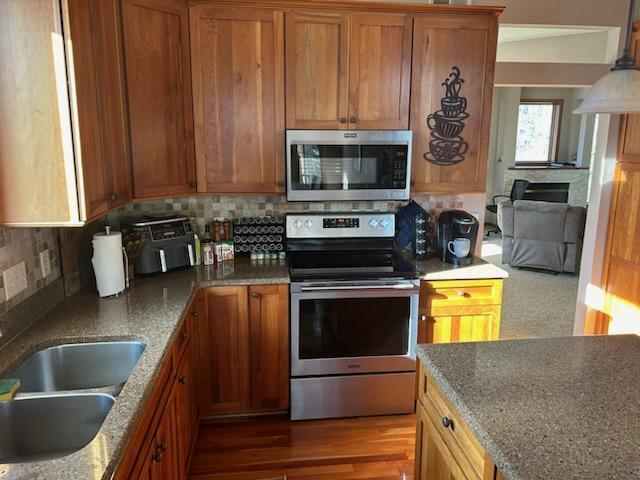 kitchen with stainless steel appliances, brown cabinets, a sink, and backsplash