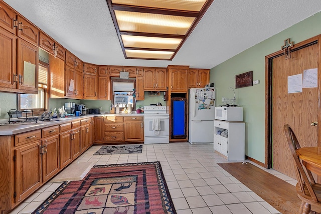 kitchen featuring white appliances, a textured ceiling, and light tile patterned floors