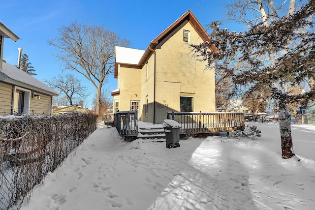 snow covered rear of property featuring a deck