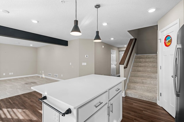 kitchen with white cabinets, beamed ceiling, decorative light fixtures, dark hardwood / wood-style flooring, and stainless steel refrigerator