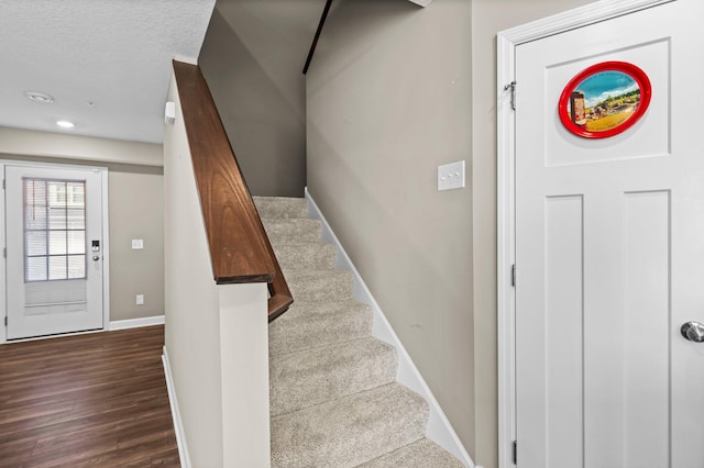 stairway with hardwood / wood-style floors and a textured ceiling