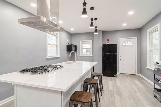 kitchen with a large island with sink, black appliances, sink, range hood, and decorative light fixtures