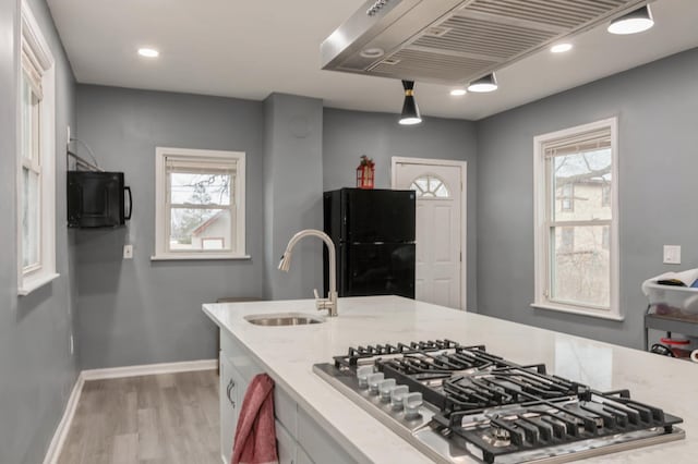 kitchen featuring black refrigerator, ventilation hood, sink, pendant lighting, and stainless steel gas stovetop