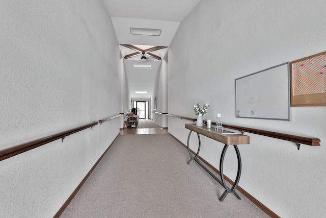 hallway featuring vaulted ceiling and carpet