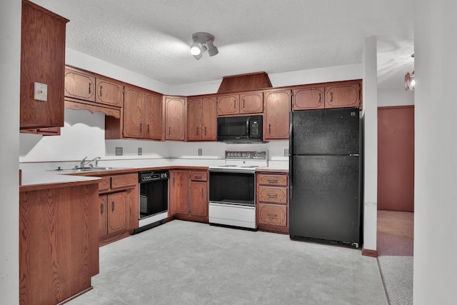 kitchen featuring black appliances, a textured ceiling, and sink