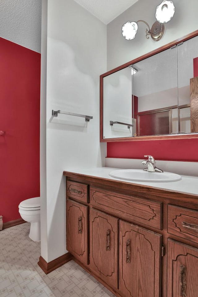 bathroom featuring a textured ceiling, vanity, and toilet