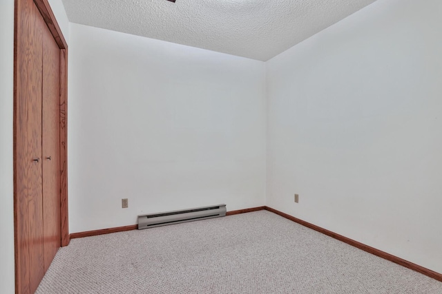 carpeted spare room featuring a baseboard radiator and a textured ceiling