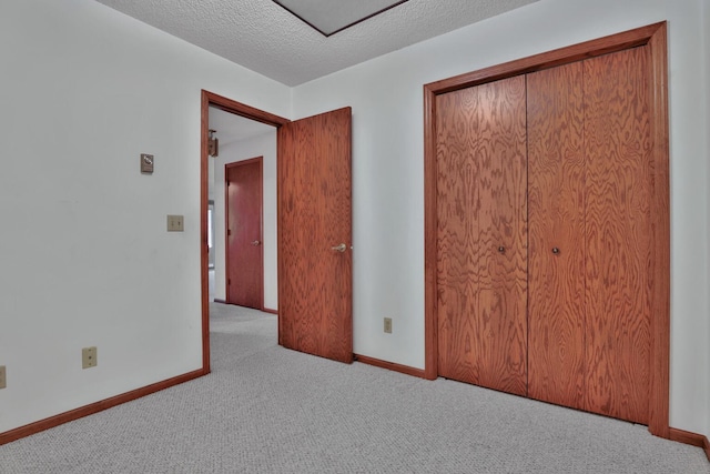 unfurnished bedroom with light colored carpet, a closet, and a textured ceiling