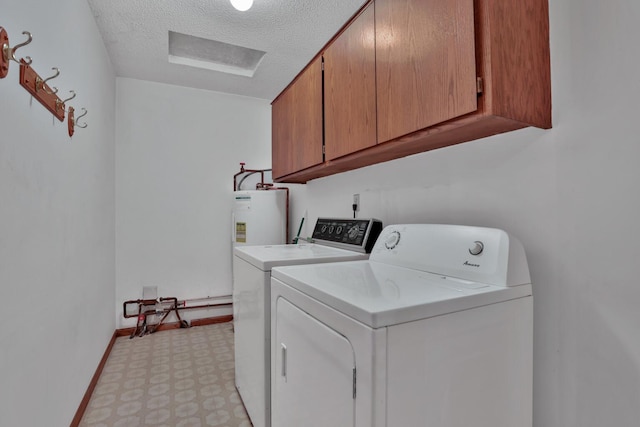 clothes washing area with water heater, washing machine and clothes dryer, a textured ceiling, and cabinets