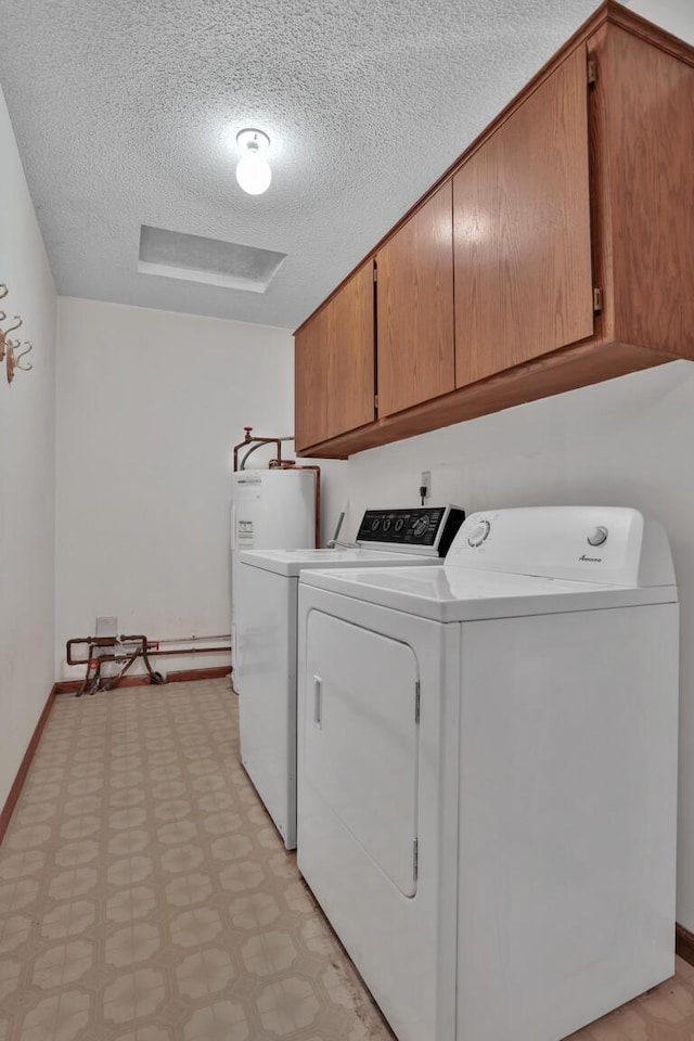 laundry area featuring a textured ceiling, cabinets, and separate washer and dryer